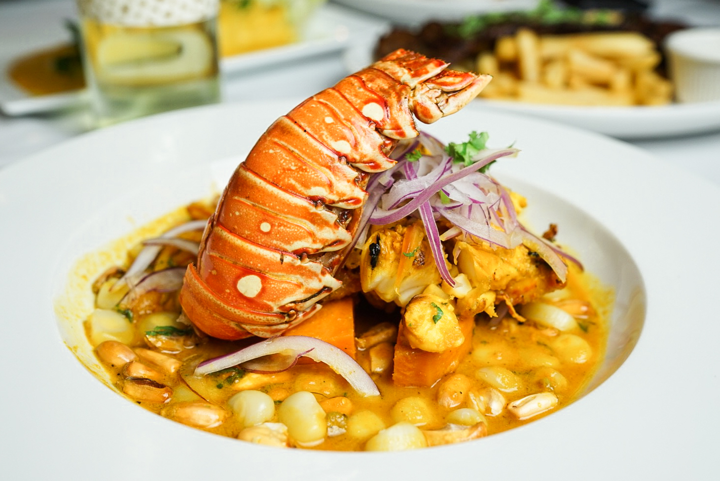 A lobster is served in a bowl of soup.