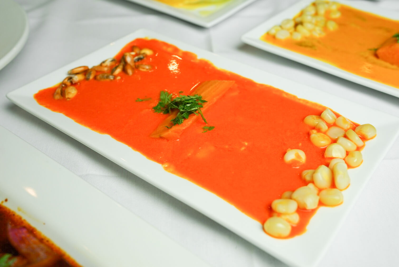 A white plate topped with a bowl of soup.