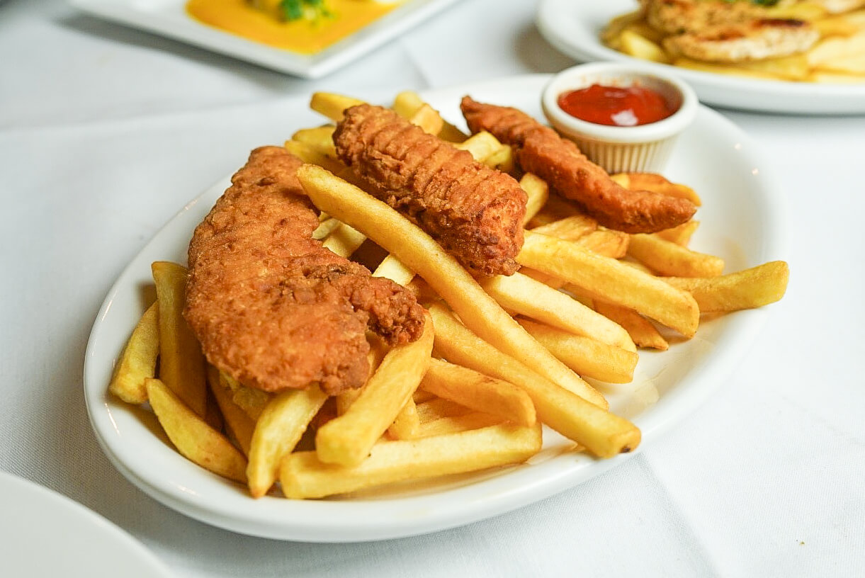 A plate of fried food with french fries and ketchup.